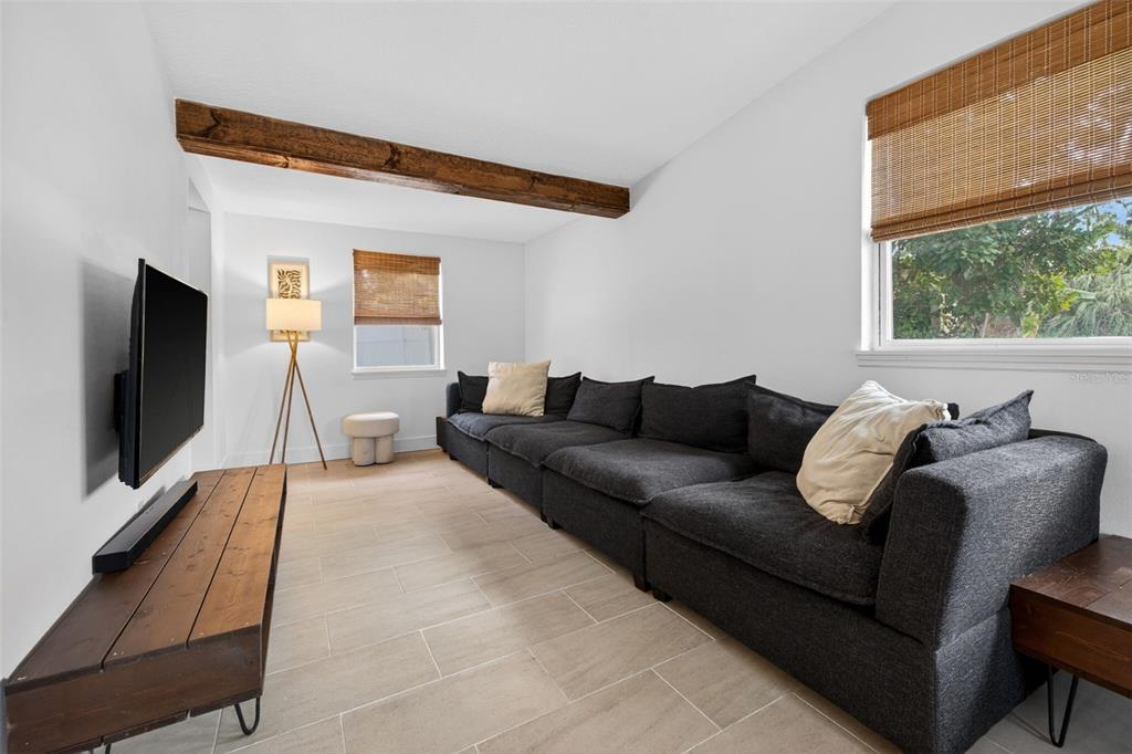 A living room features a large dark sectional sofa, a wooden beam, and tile flooring — 101 40TH AVENUE SE, ST PETERSBURG, FL