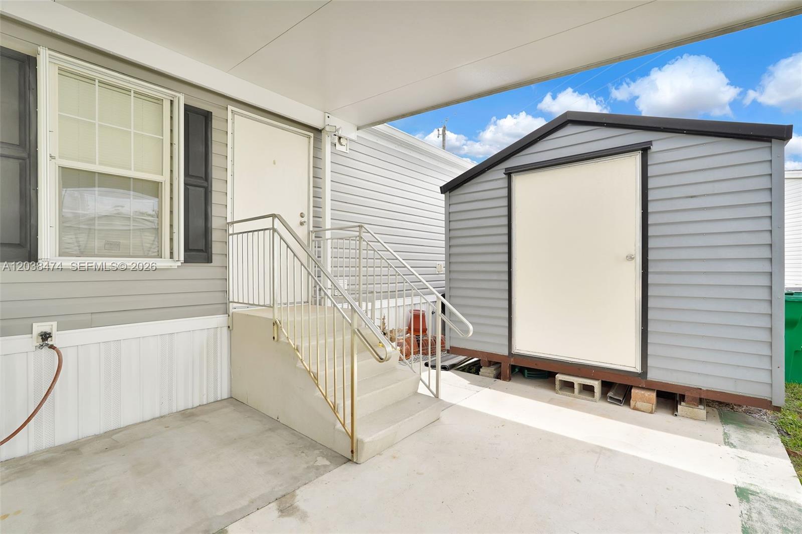 A concrete patio features a set of stairs leading to a door and a shed — 8709 SW 17th Ct, Davie FL 33324, DAVIE, FL