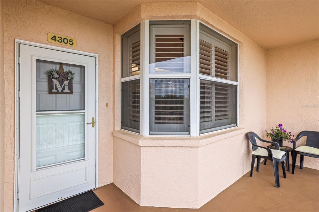 A front porch features a white door, a bay window with shutters, and two chairs — 6399 SHORELINE DRIVE UNIT 4305, ST PETERSBURG, FL