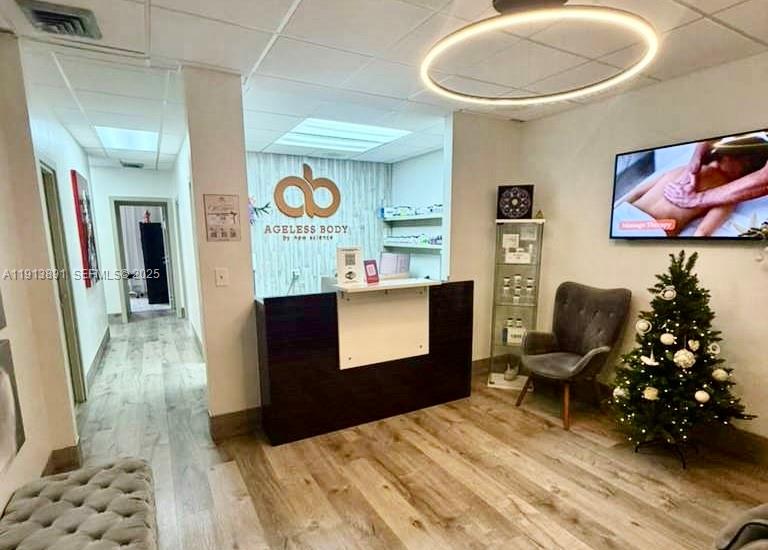 A reception area features a dark wood desk, a gray armchair, and a Christmas tree — 2500 E Hallandale Beach Blvd, Hallandale Beach FL 33009, HALLANDALE BEACH, FL