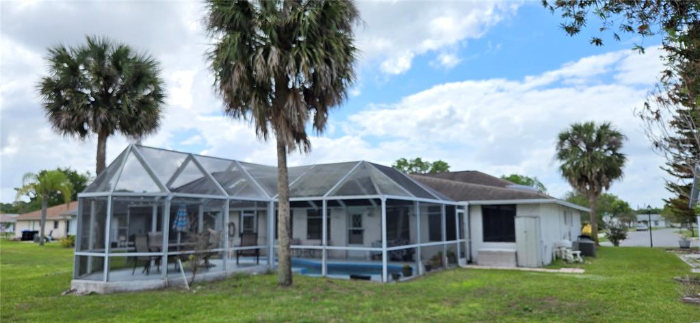 A backyard view of a house with a screened-in pool enclosure and palm trees — 5445 SANDY HILL DRIVE, ORLANDO, FL