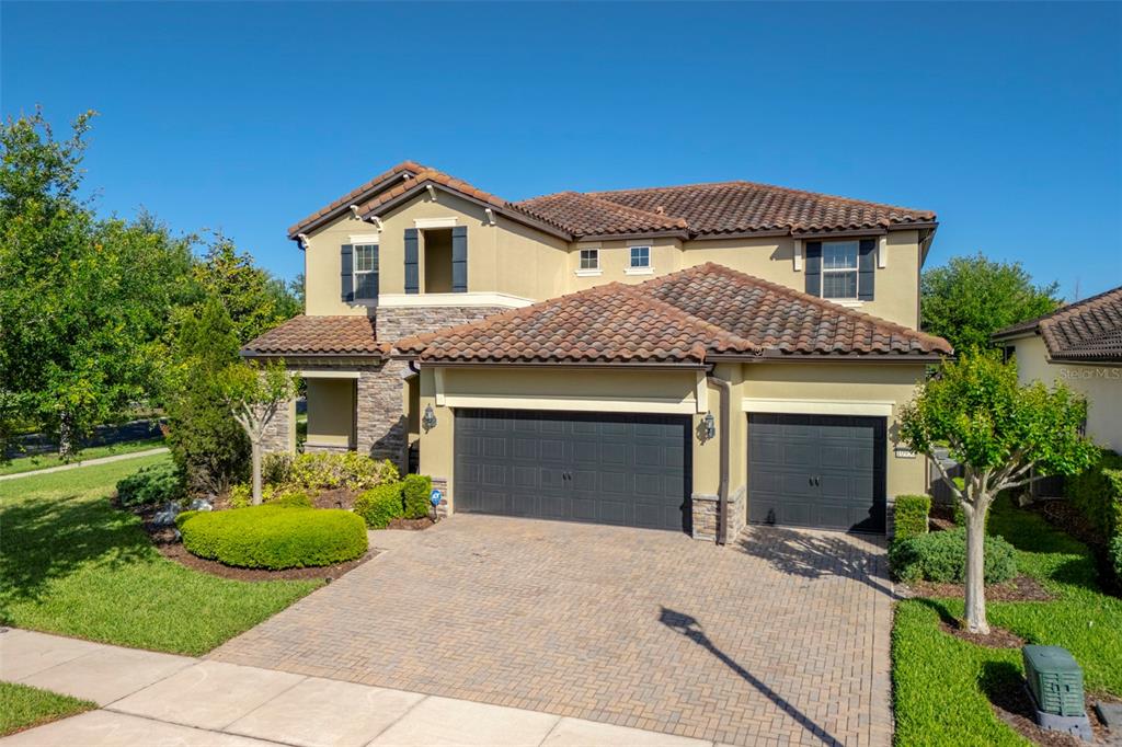 A two-story house with a tile roof, stone accents, and a three-car garage — 10950 CITRON OAKS DRIVE, ORLANDO, FL