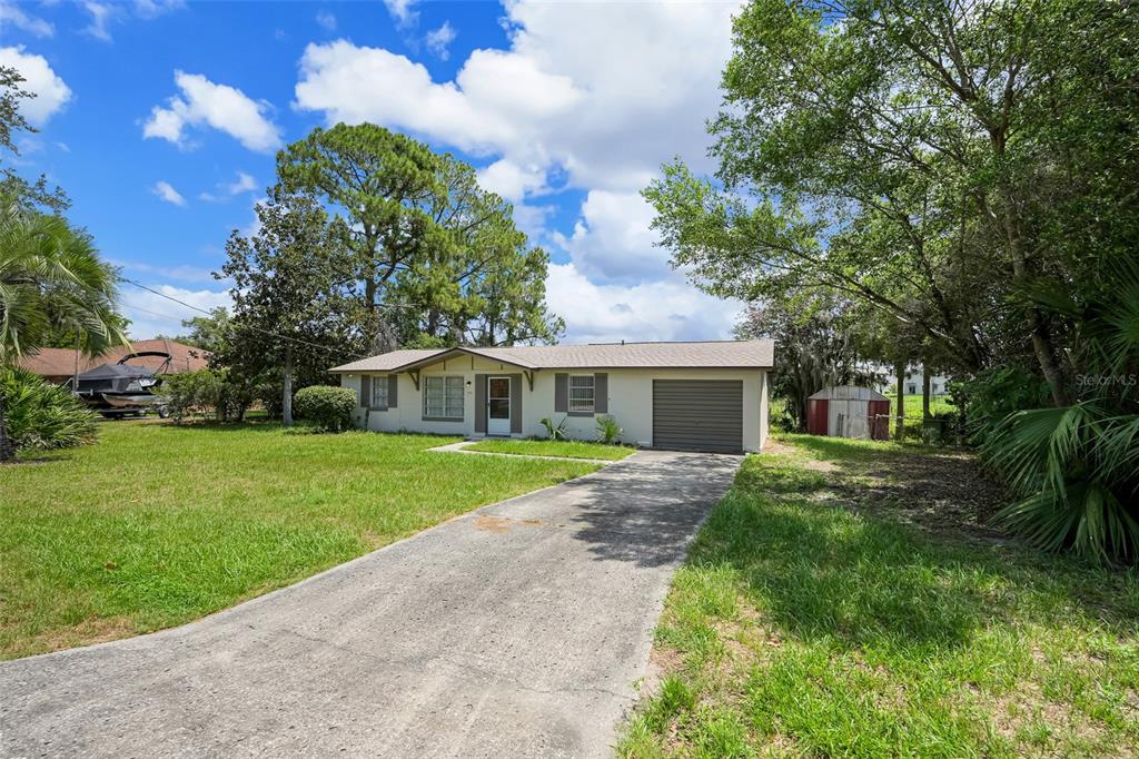 A single-story house with a concrete driveway, a garage, and a lawn under a blue sky — 520 N LACY CIRCLE, DELTONA, FL