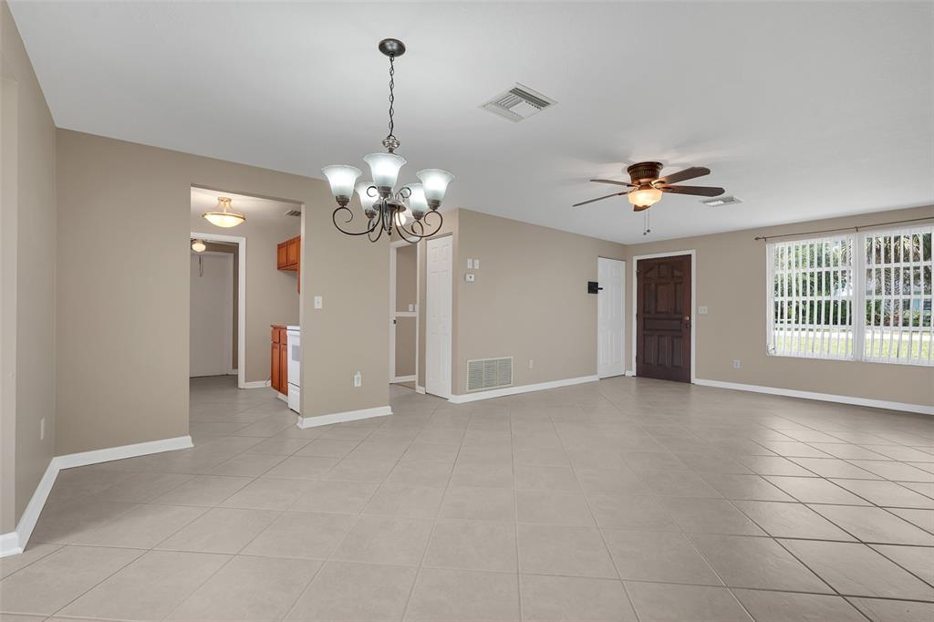 A spacious living room features light tile flooring, a ceiling fan, and a dining chandelier — 520 N LACY CIRCLE, DELTONA, FL