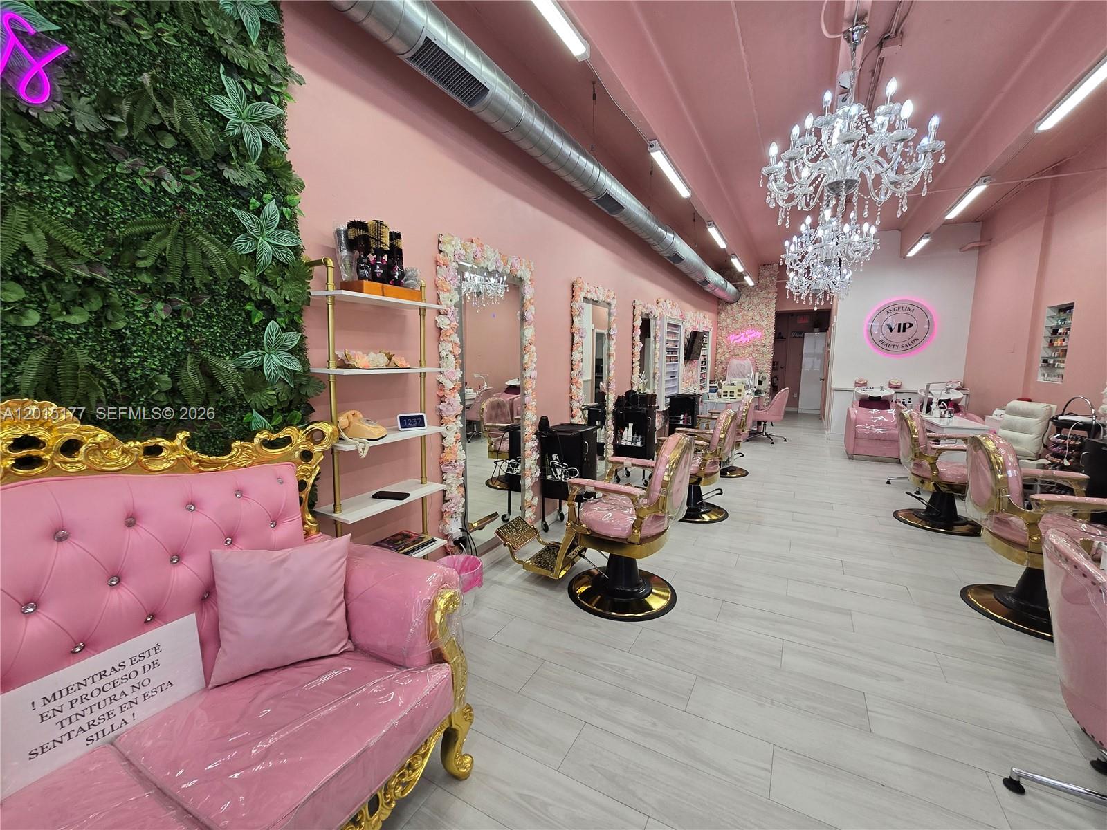 A pink-themed beauty salon features gold-accented chairs, floral-framed mirrors, and a green wall — MIAMI, FL