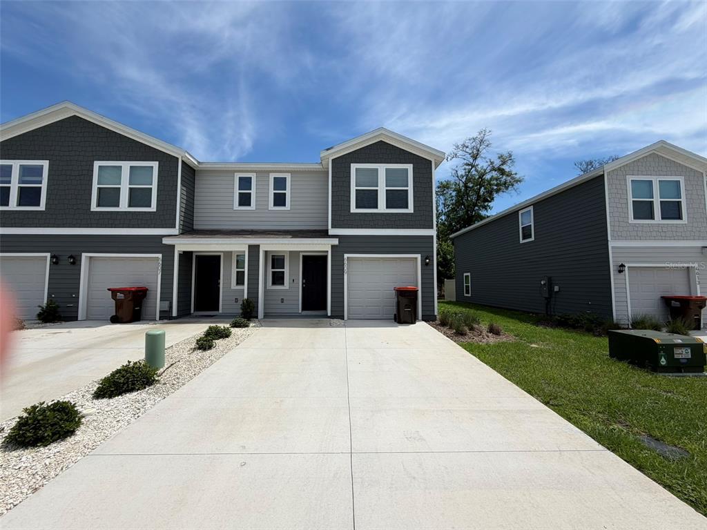 A two-story townhouse exterior features gray siding, a concrete driveway, and attached garages — 6609 SW 81ST LOOP, OCALA, FL