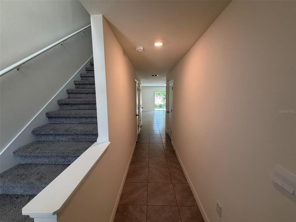 A hallway with tile flooring leads toward a glass door, with carpeted stairs on the left — 6609 SW 81ST LOOP, OCALA, FL