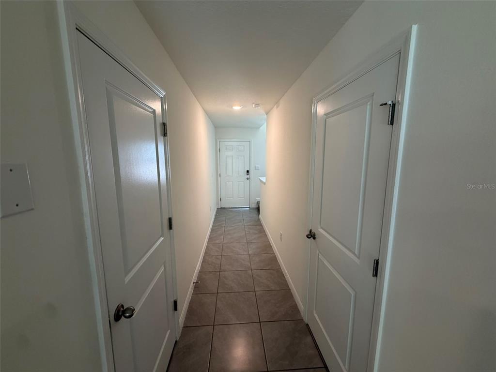 A hallway with tiled flooring leads to a white door at the far end — 6609 SW 81ST LOOP, OCALA, FL