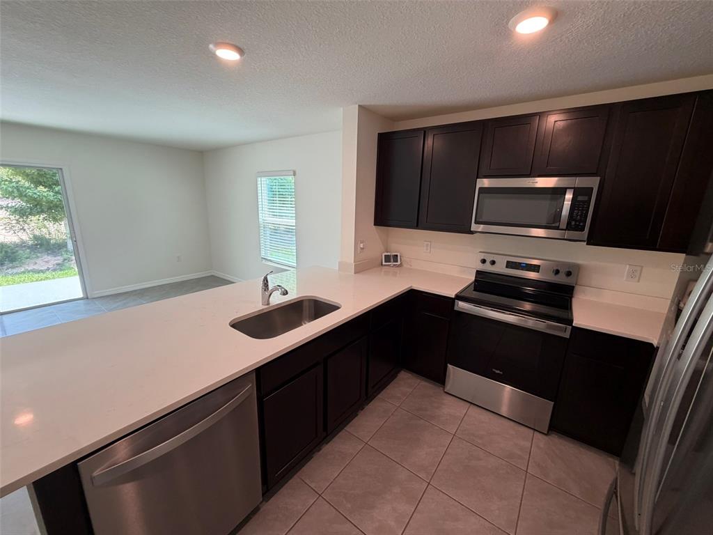 A kitchen features dark wood cabinets, stainless steel appliances, and white countertops — 6609 SW 81ST LOOP, OCALA, FL