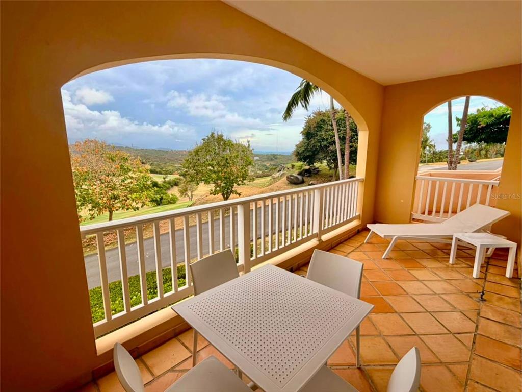 A covered balcony features a dining set, lounge chairs, and a view of a golf course — 1000 LAS CASITA I, EL CONQUISTADOR AVE. UNIT 5380, FAJARDO, PR