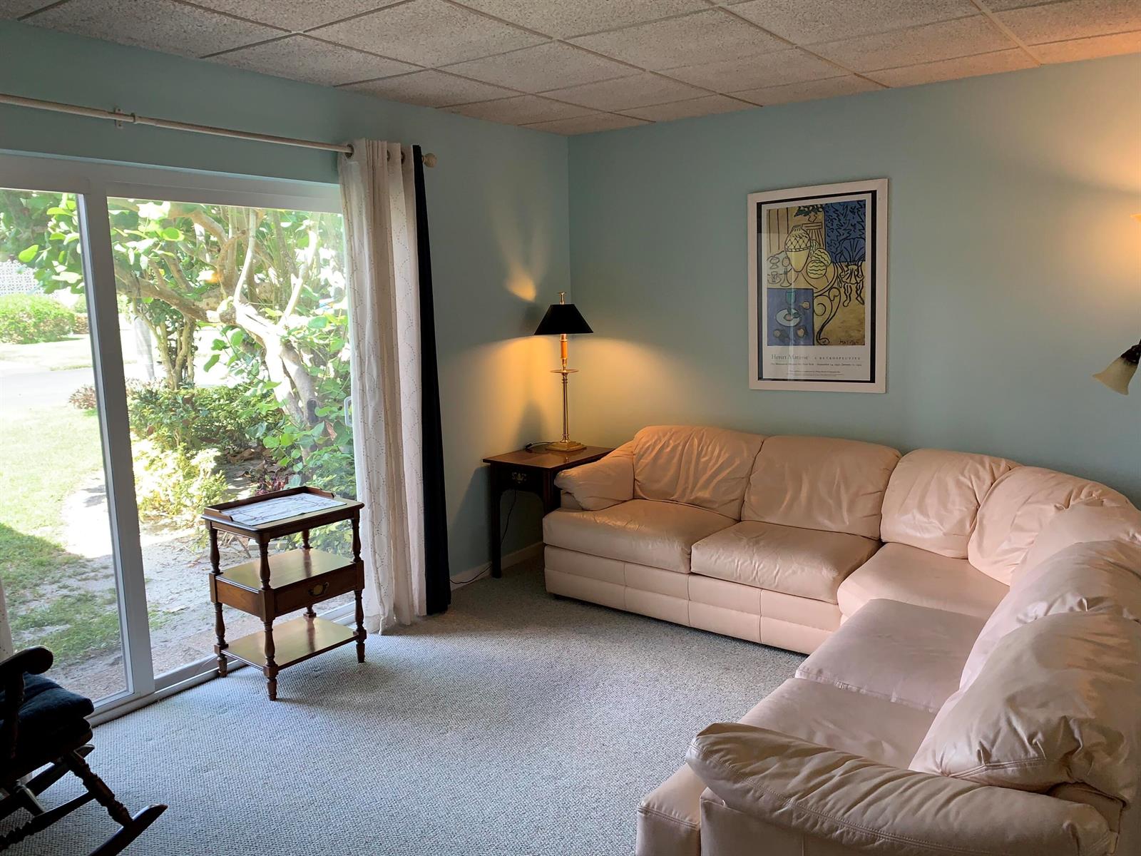 A living room with a light-colored sectional sofa, a side table, and a sliding glass door — 100 S South Boulevard # 1c, Boynton Beach FL 33435, BOYNTON BEACH, FL