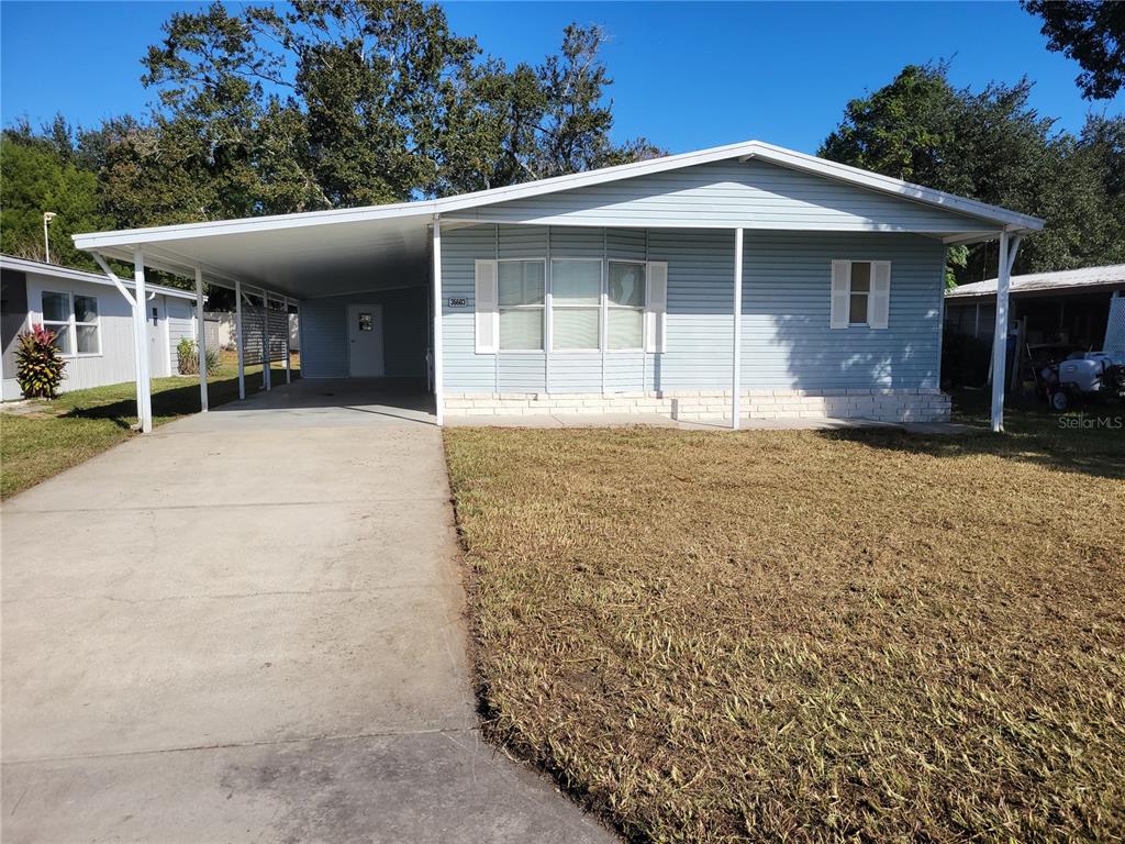 A light blue single-story house with a carport and a concrete driveway — 36603 JODI AVENUE, ZEPHYRHILLS, FL