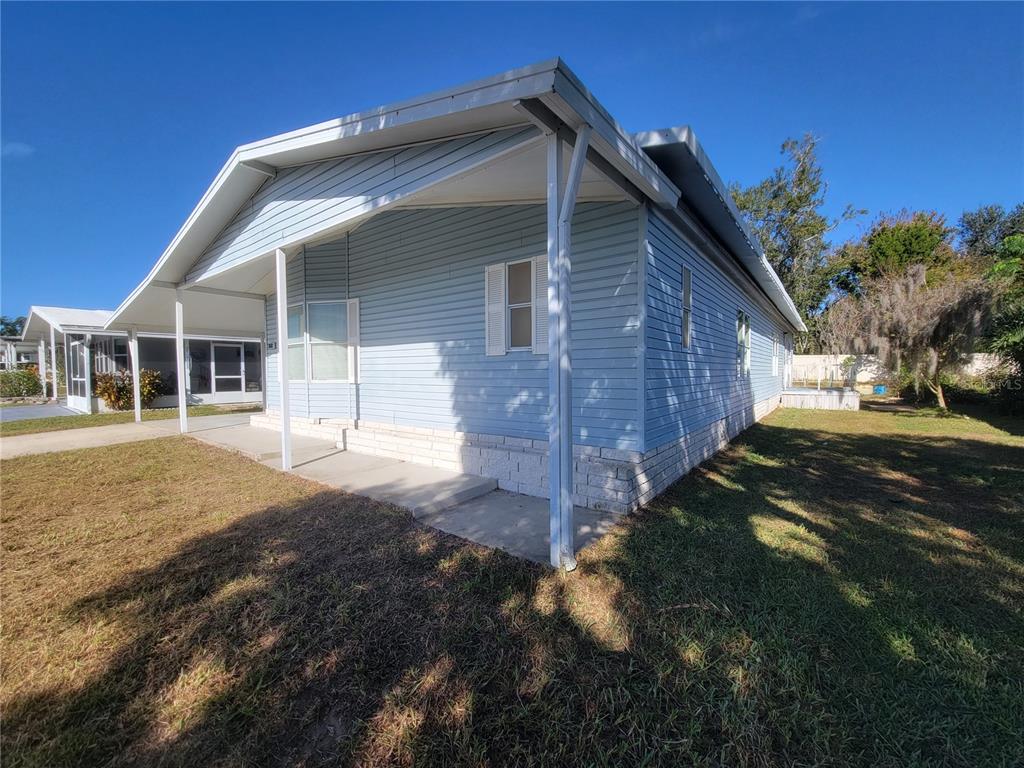 A light blue mobile home with a covered front porch and a white brick foundation — 36603 JODI AVENUE, ZEPHYRHILLS, FL