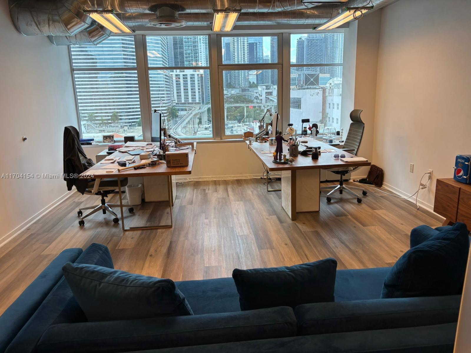 An office space with two desks, wood flooring, and large windows overlooking a city skyline — 14 NE 1st Ave, Miami FL 33132, MIAMI, FL