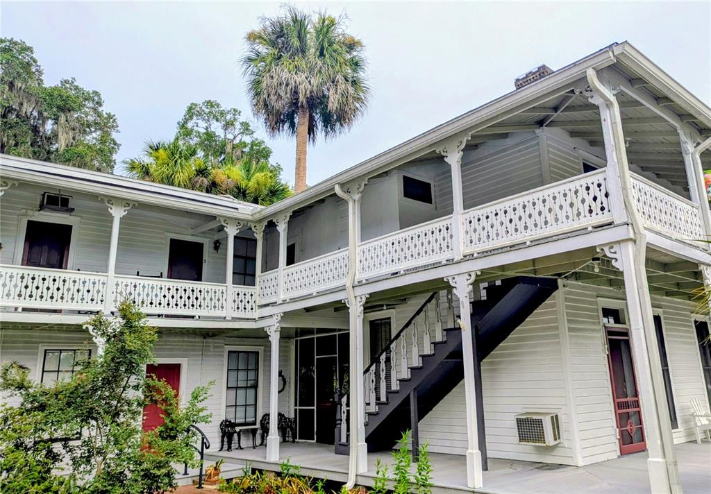 A two-story white wooden building features a wraparound balcony with decorative railings and exterior stairs — 6635 SE 221ST STREET UNIT 3, HAWTHORNE, FL