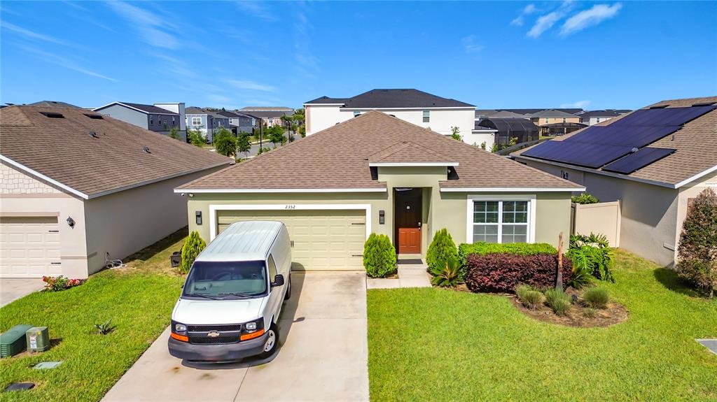 A single-story house with a light green exterior, a two-car garage, and a white van parked — 2352 WHITE POPPY DRIVE, KISSIMMEE, FL