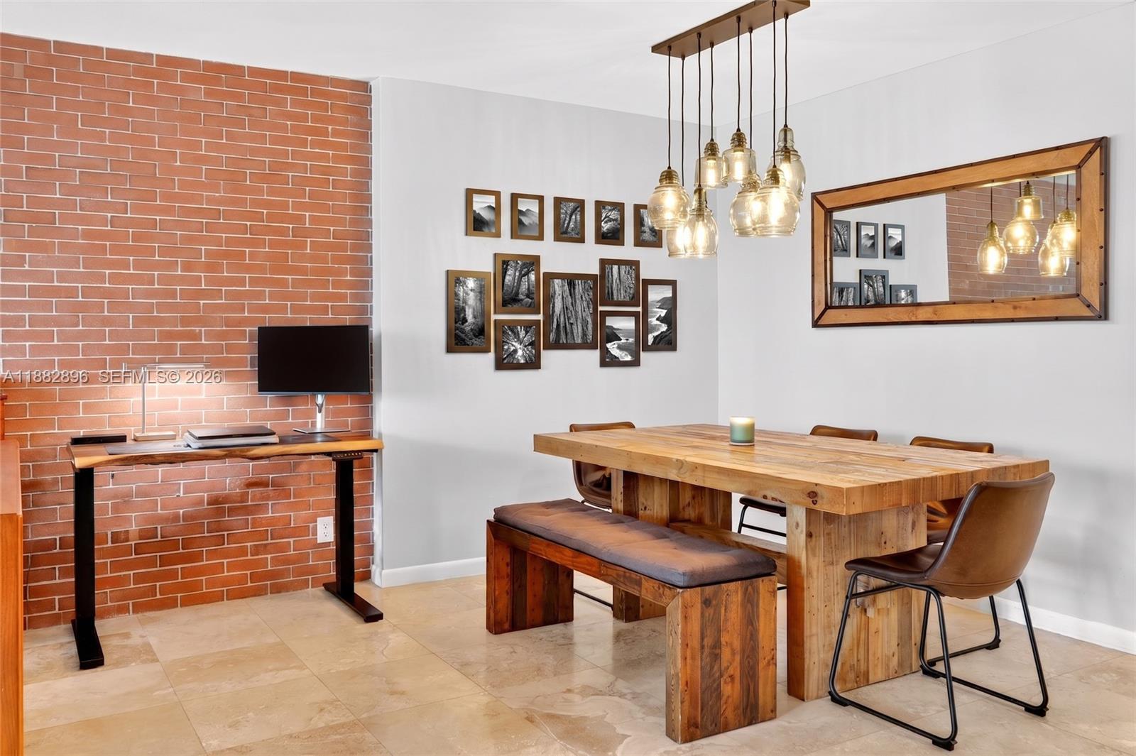 A dining room features a wooden table, a bench, chairs, and a brick accent wall — 5700 Collins Ave # 3M, Miami Beach FL 33140, MIAMI BEACH, FL