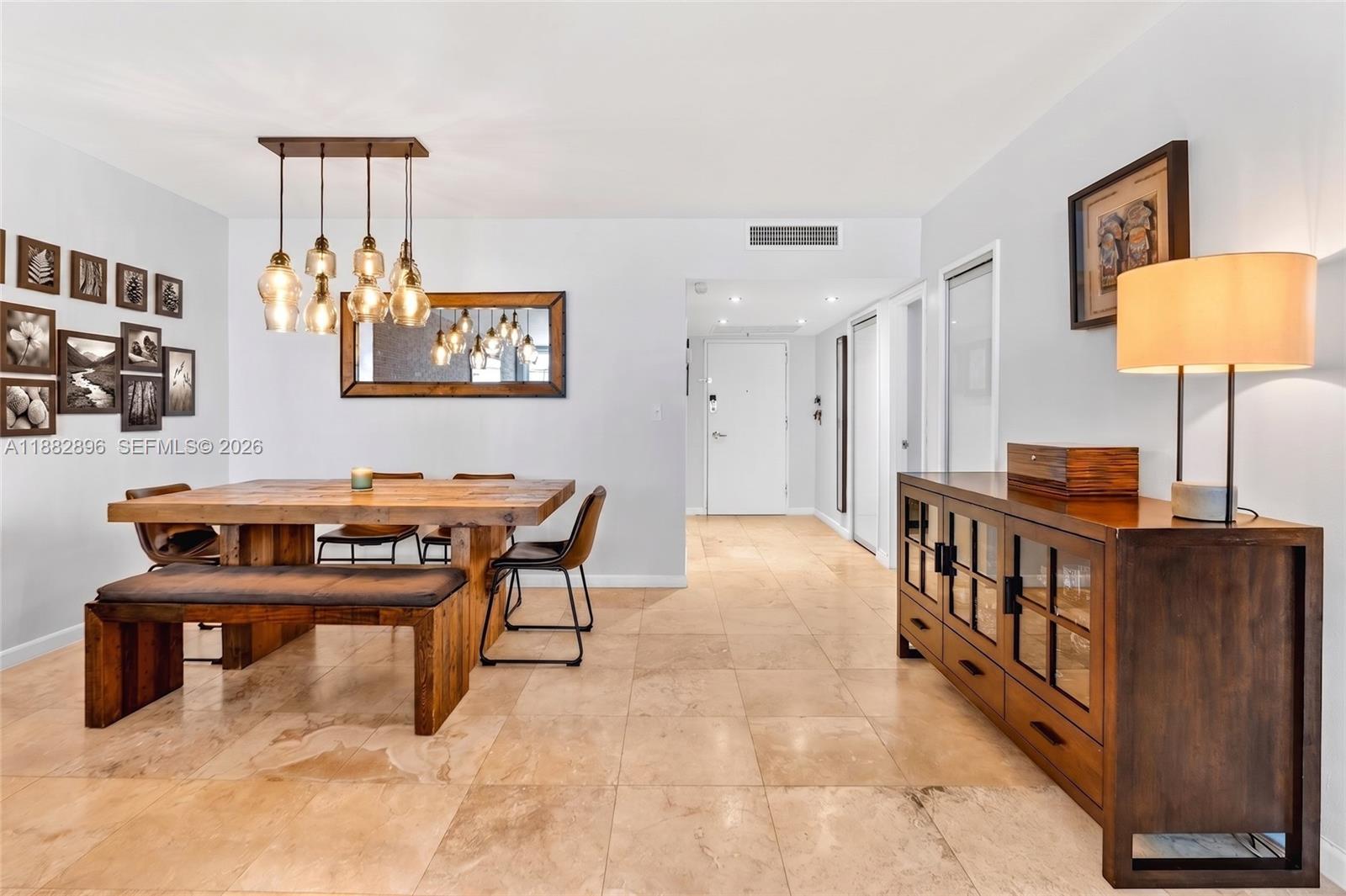 A dining room features a wooden table, bench, chairs, and a sideboard on tile flooring — 5700 Collins Ave # 3M, Miami Beach FL 33140, MIAMI BEACH, FL