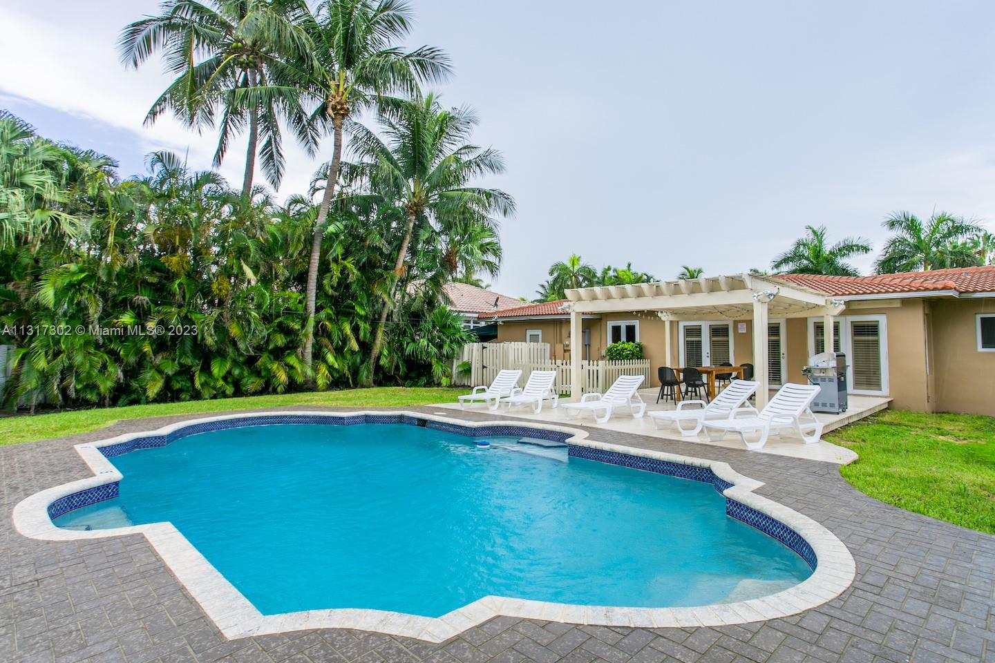 A backyard features a swimming pool, a patio with lounge chairs, and a pergola — 714 Harrison St, Hollywood FL 33019, HOLLYWOOD, FL
