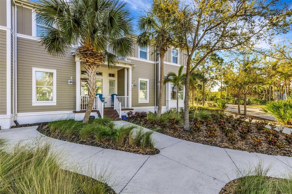 A two-story house with tan siding, a front porch, and a concrete walkway — 289 SAPPHIRE LAKE DRIVE UNIT 202, BRADENTON, FL