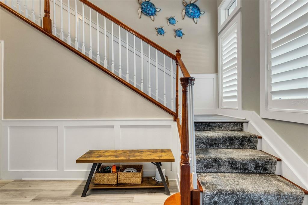 A staircase with patterned carpet and a wooden handrail sits next to a wooden bench — 289 SAPPHIRE LAKE DRIVE UNIT 202, BRADENTON, FL