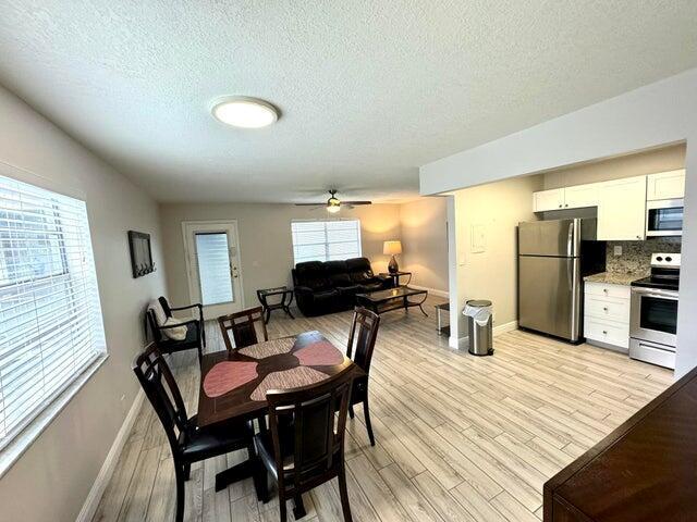 An open-concept living area features a dining set, a sofa, and a kitchen with appliances — 127 Flanders # C, Delray Beach FL 33484, DELRAY BEACH, FL