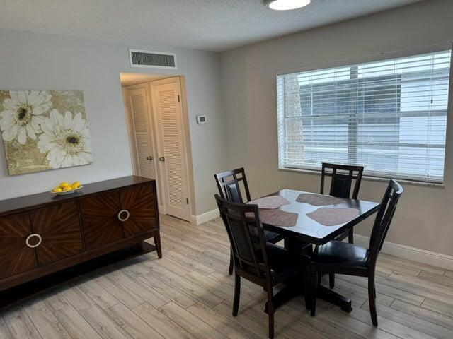 A dining area features a dark wood sideboard, a square table with four chairs, and tile flooring — 127 Flanders # C, Delray Beach FL 33484, DELRAY BEACH, FL