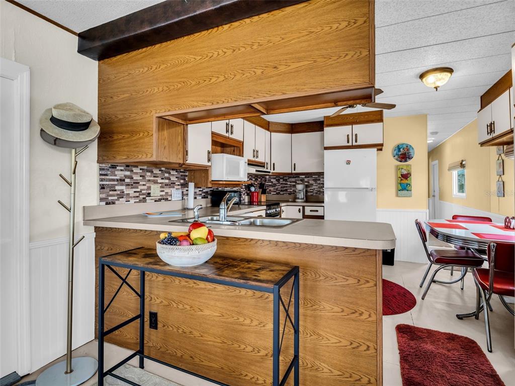 A kitchen with wood-look cabinets, a breakfast bar, and a dining area with red chairs — 800 CHESAPEAKE DRIVE UNIT 62, TARPON SPRINGS, FL