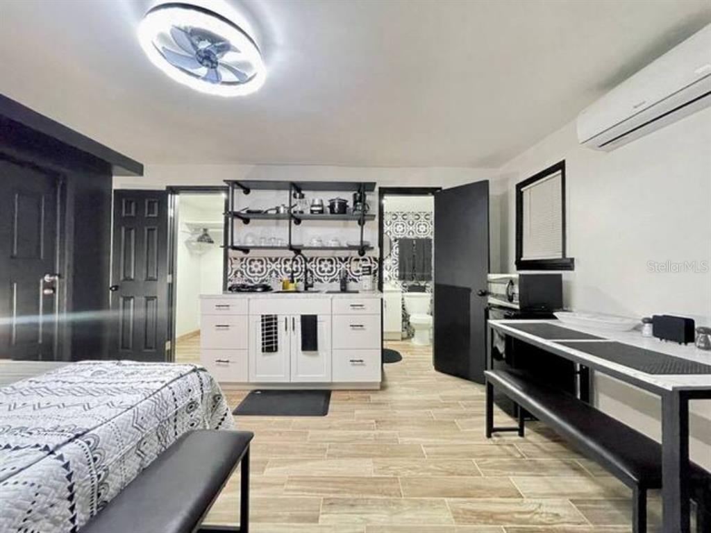A studio apartment features a kitchenette with open shelving, white cabinets, and patterned tile backsplash — 1731 GRAYSON DR UNIT 3, ORLANDO, FL