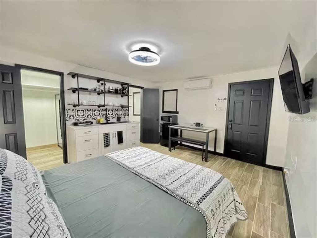 A bedroom features a kitchenette with open shelving, a bed, and a small dining table — 1731 GRAYSON DR UNIT 3, ORLANDO, FL