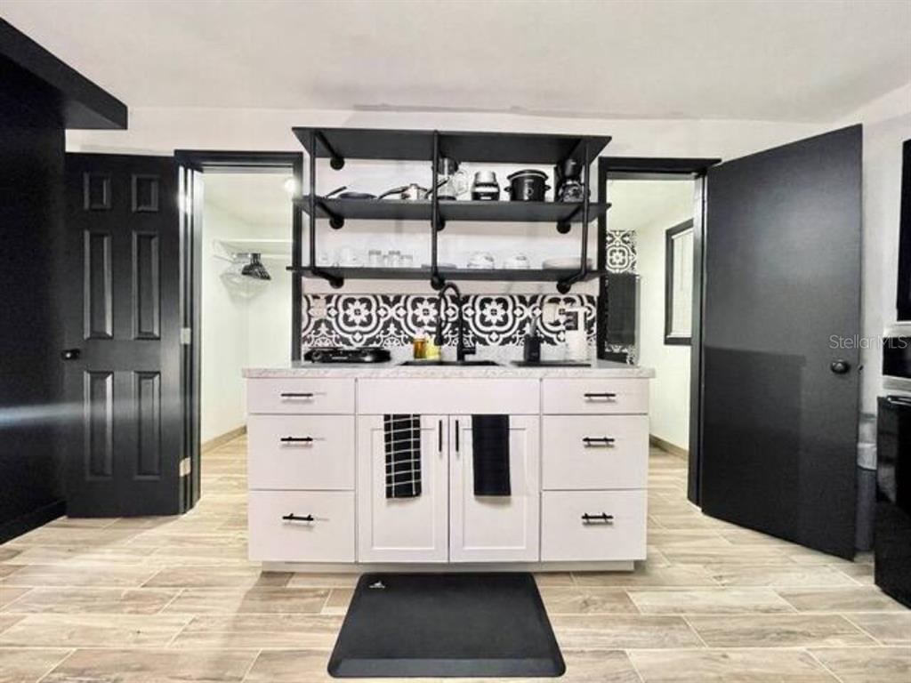 A kitchen area features white cabinets, open industrial-style shelving, and a patterned tile backsplash — 1731 GRAYSON DR UNIT 3, ORLANDO, FL