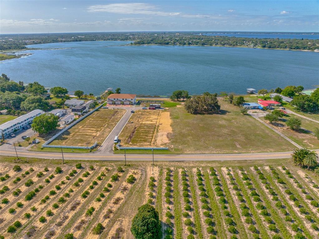 An aerial view shows vacant land parcels situated between a road and a large lake — 1877 ARBUCKLE CREEK ROAD, SEBRING, FL