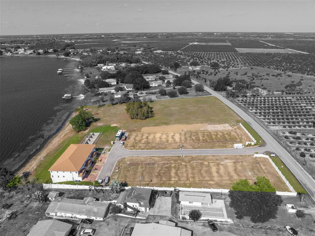 An aerial view shows a waterfront property with a large house and several vacant lots — 1877 ARBUCKLE CREEK ROAD, SEBRING, FL