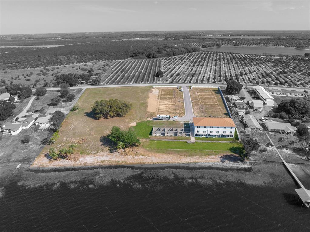 An aerial view shows a large waterfront property with a building, trees, and open land — 1877 ARBUCKLE CREEK ROAD, SEBRING, FL