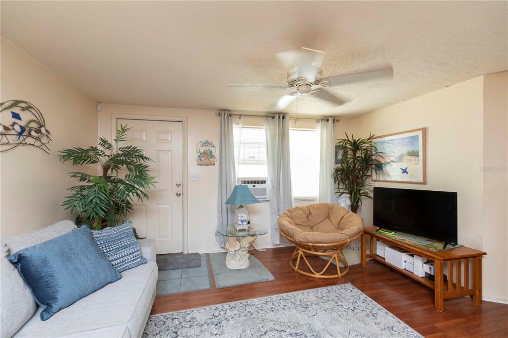 A living room features a sofa, a papasan chair, a television, and a ceiling fan — 8431 SUNNYDALE DRIVE, HUDSON, FL