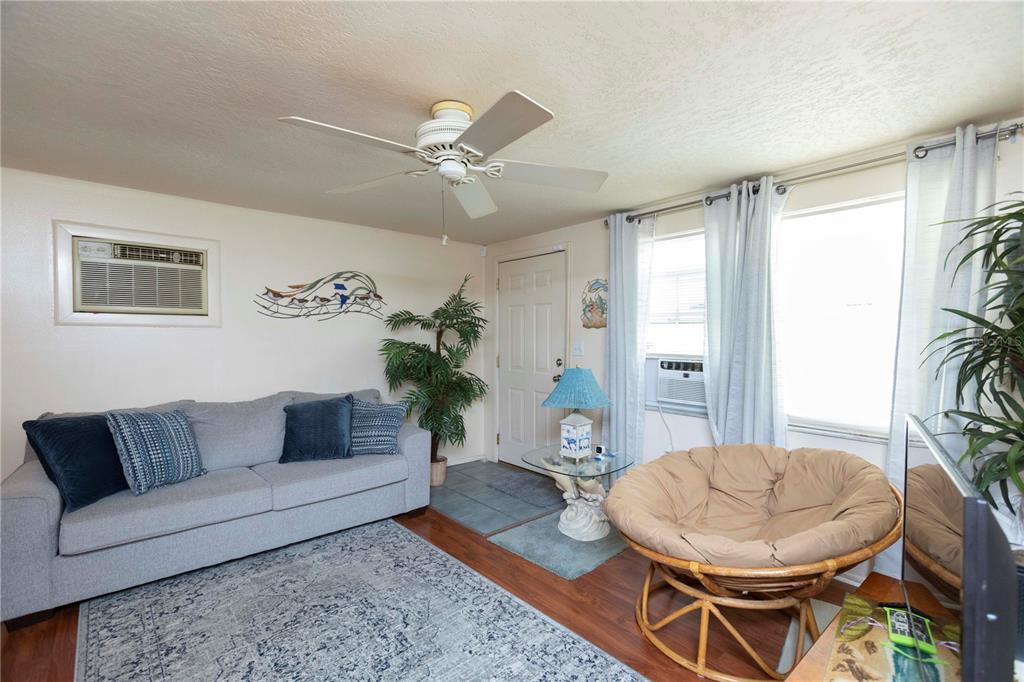 A living room features a gray sofa, a rattan chair, and a ceiling fan — 8431 SUNNYDALE DRIVE, HUDSON, FL