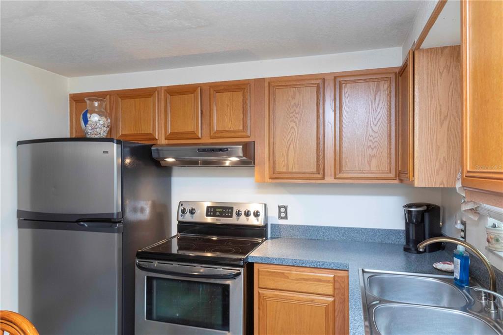 A kitchen features wood cabinets, stainless steel appliances, and a blue laminate countertop — 8431 SUNNYDALE DRIVE, HUDSON, FL