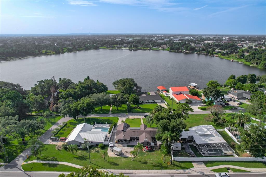 An aerial view shows several houses with swimming pools situated along the shore of a lake — 128 N LAKE FLORENCE DRIVE, WINTER HAVEN, FL