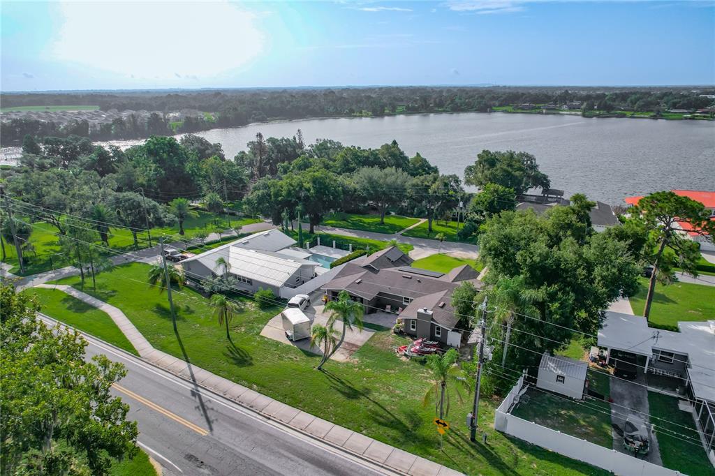 An aerial view shows a residential property with a pool, driveway, and lakefront access — 128 N LAKE FLORENCE DRIVE, WINTER HAVEN, FL