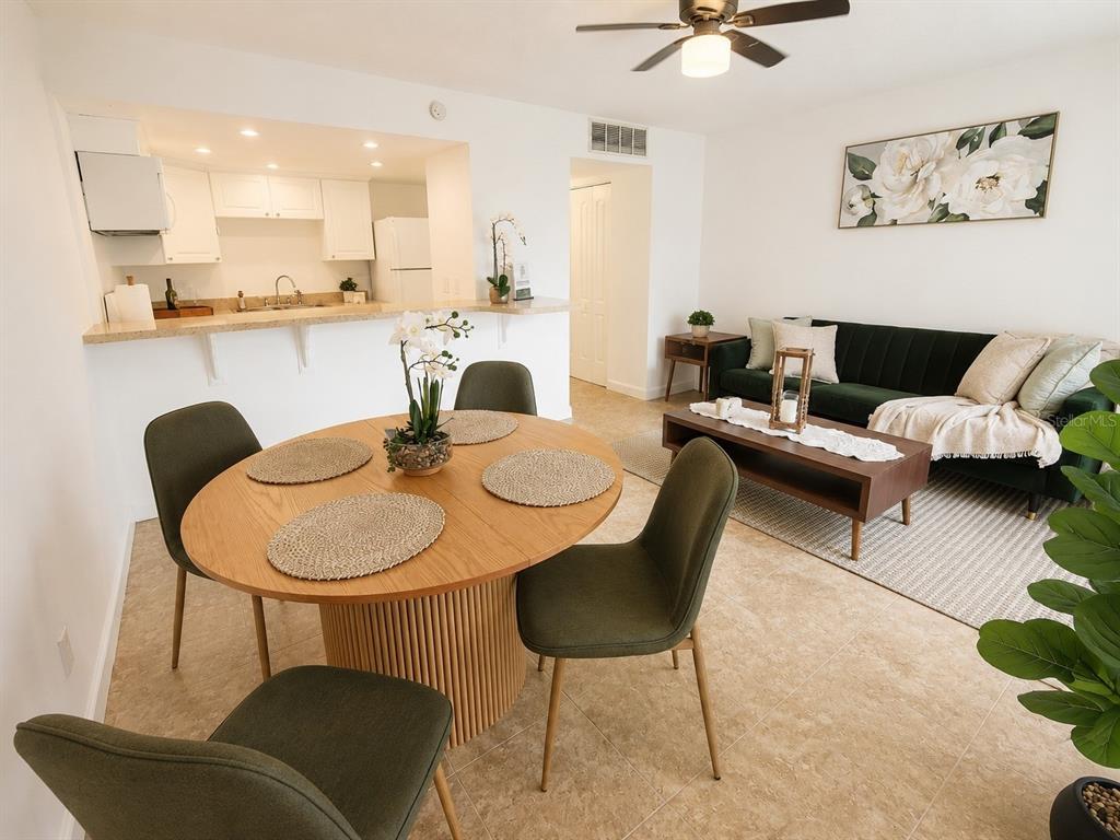An open-concept living and dining area features a round wooden table and a green sofa — 5820 N CHURCH AVENUE UNIT 112, TAMPA, FL