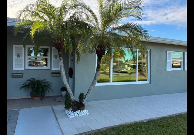 The exterior of a gray house features a palm tree, tiled patio, and large windows — 917 S Drive Terrace # B, Delray Beach FL 33445, DELRAY BEACH, FL