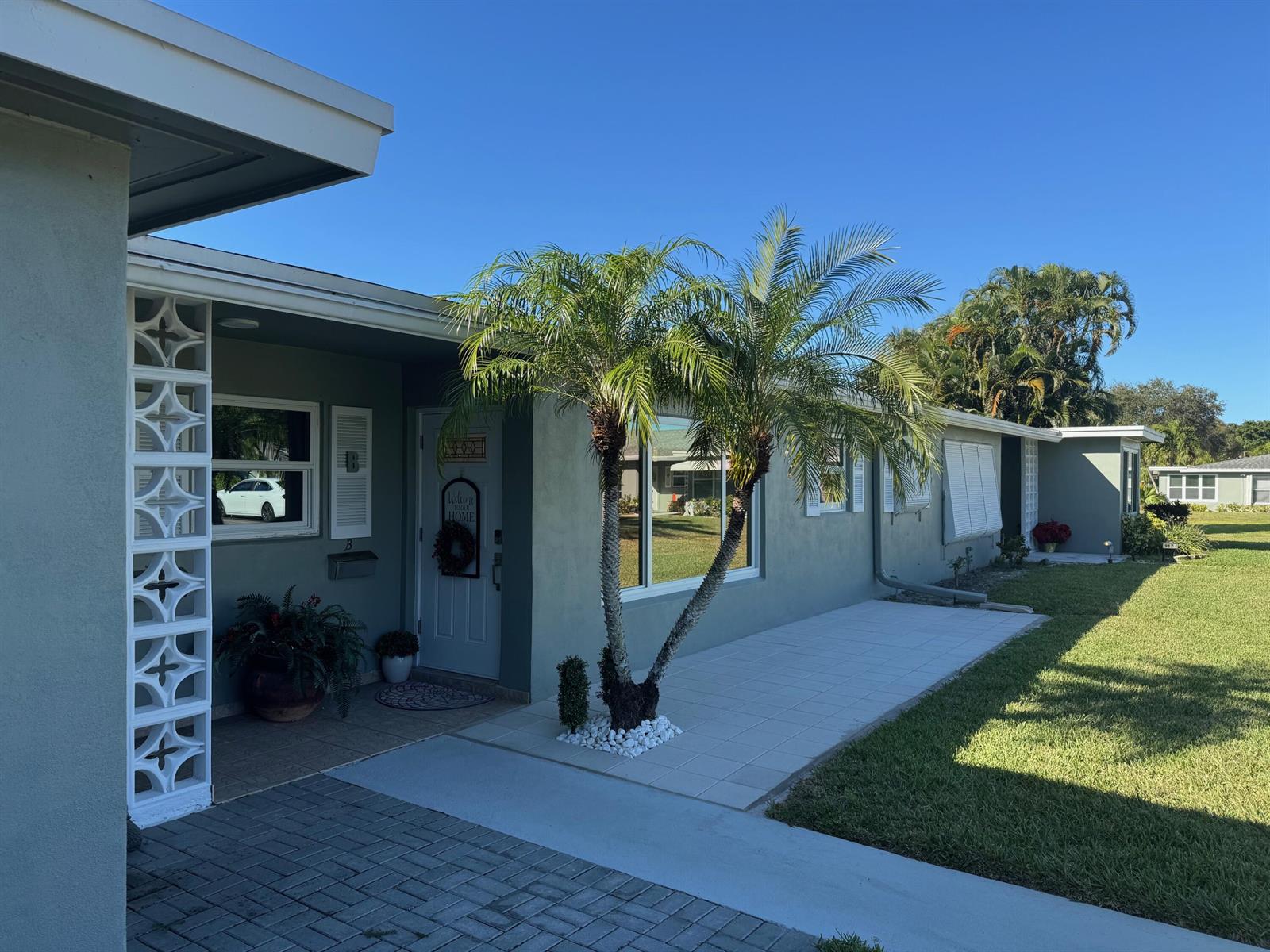 A single-story house exterior features a palm tree, a tiled patio, and decorative concrete blocks — 917 S Drive Terrace # B, Delray Beach FL 33445, DELRAY BEACH, FL