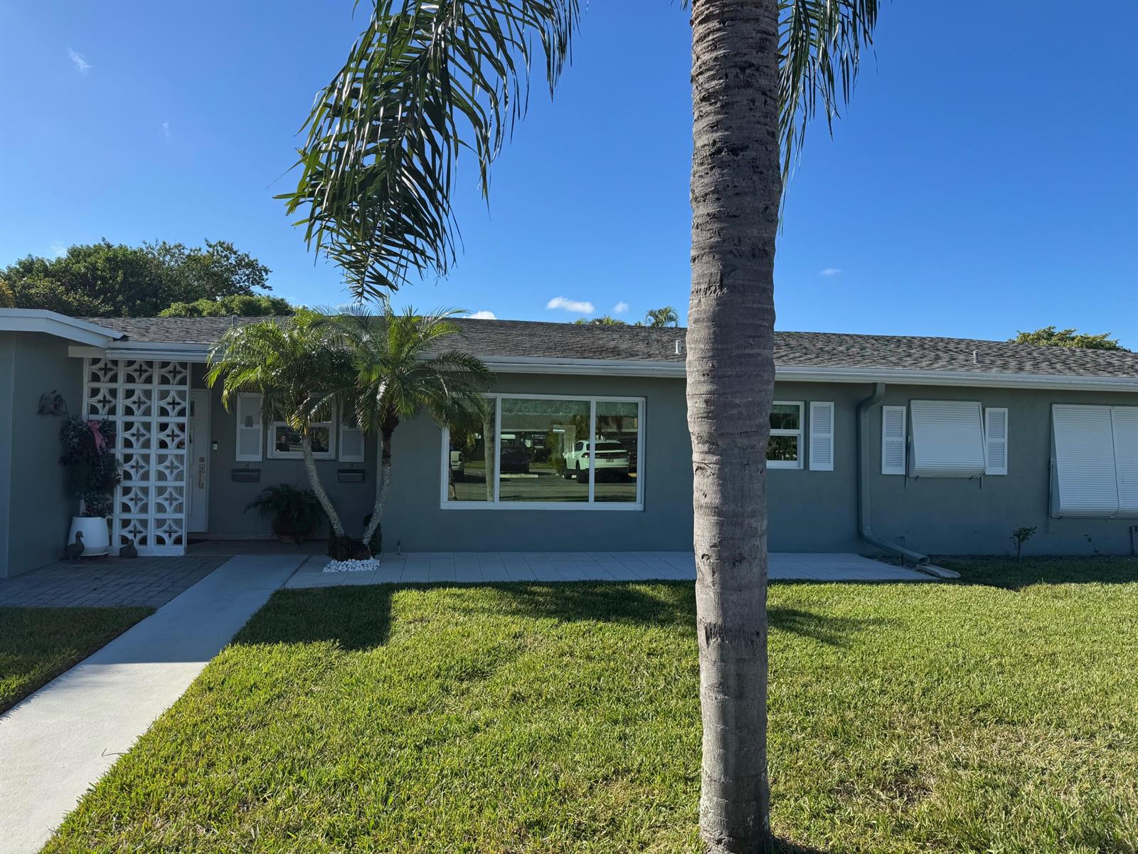 A single-story gray house with a palm tree, a front patio, and decorative lattice screen — 917 S Drive Terrace # B, Delray Beach FL 33445, DELRAY BEACH, FL