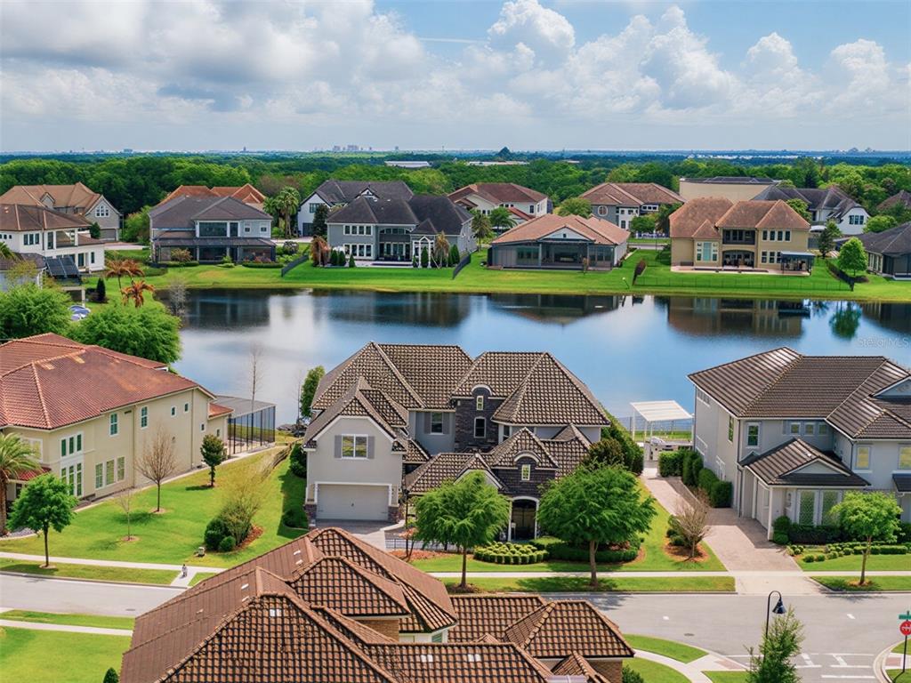 An aerial view of a suburban neighborhood featuring large houses surrounding a central lake — 7654 BLUE QUAIL LANE, ORLANDO, FL