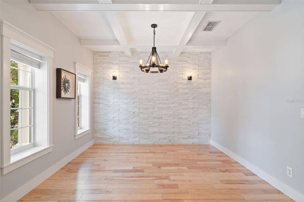 A dining room with a white stone accent wall, hardwood floors, and a chandelier — 5362 CHATAS LANE, ORLANDO, FL