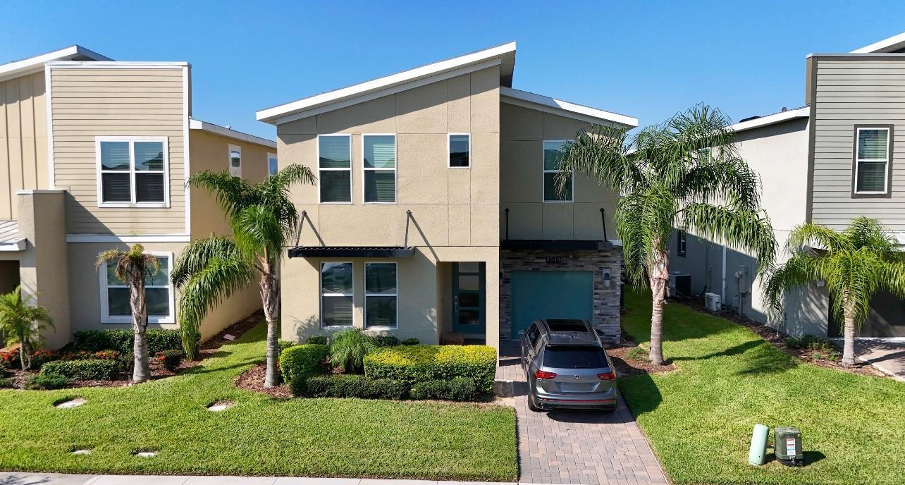 A two-story house with a tan stucco exterior, a paved driveway, and palm trees — 8944 Cabot Cliffs Drive, Davenport FL 33896, DAVENPORT, FL