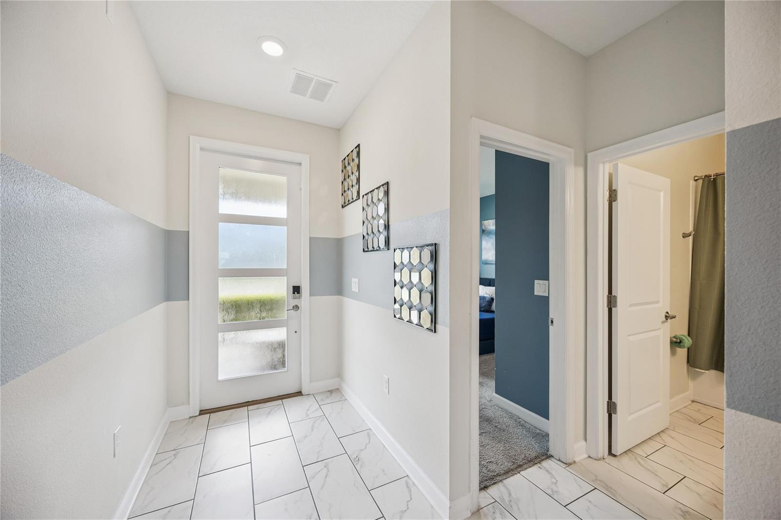 A bright entryway features white tile floors, a glass-paneled front door, and gray-painted wall accents — 8944 Cabot Cliffs Drive, Davenport FL 33896, DAVENPORT, FL