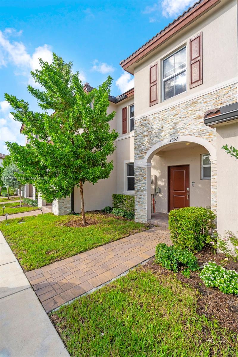 A two-story residential building features a stone-accented entryway, a brown door, and a paved walkway — 2357 NW 122nd Ter, Miami FL 33167, MIAMI, FL