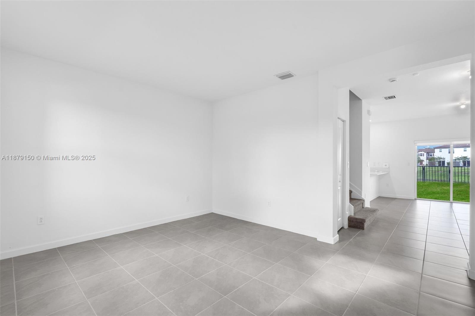 This room features white walls, gray tile flooring, and an adjacent staircase leading upstairs — 2357 NW 122nd Ter, Miami FL 33167, MIAMI, FL