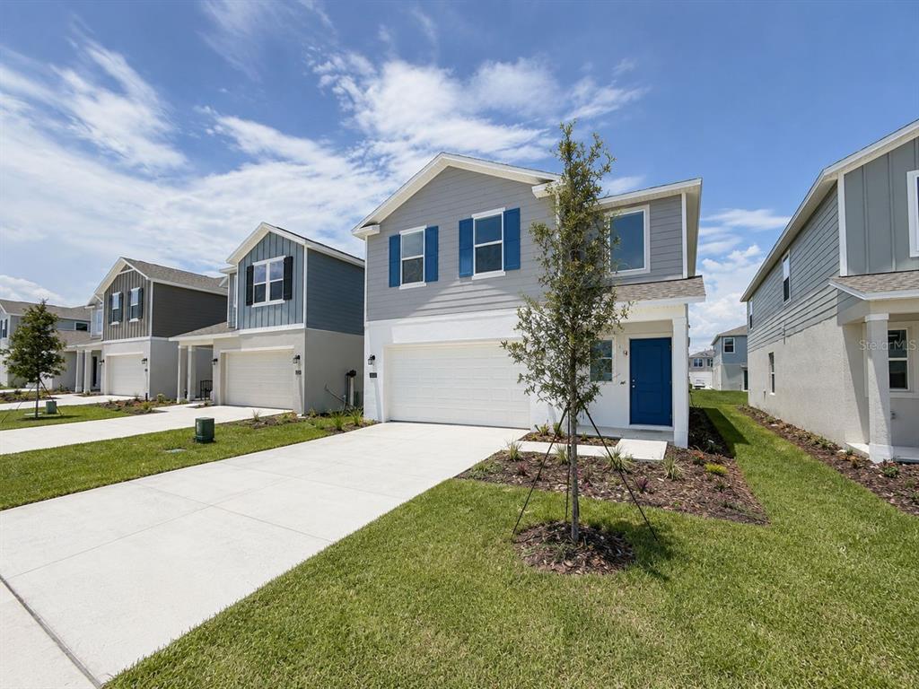 A two-story suburban house with a white garage, blue front door, and gray siding — 2432 BLUESTONE ROAD, HAINES CITY, FL